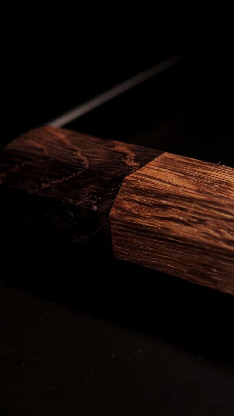 Egetræsskæftet på RAW OAK THOR kødøkse, hvor det møder klingen, med synlig åretegning.