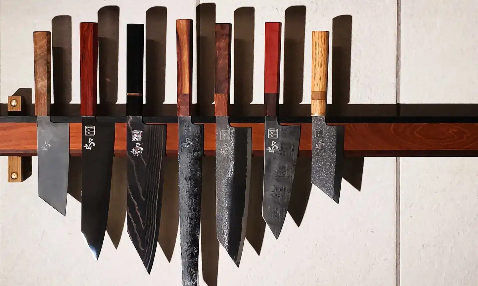 Syv specialfremstillede knive med forskellige skæfter på en vægliste